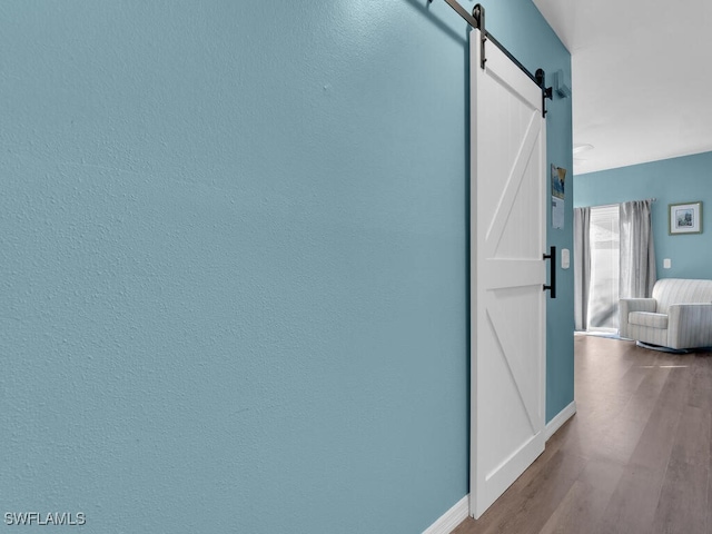 hall with a barn door and hardwood / wood-style floors