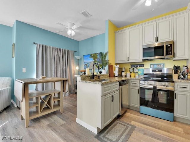 kitchen featuring stainless steel appliances, sink, light hardwood / wood-style flooring, and kitchen peninsula