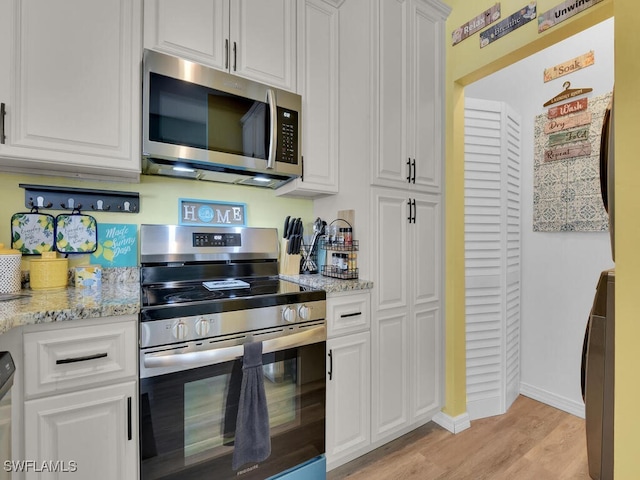 kitchen with white cabinetry, appliances with stainless steel finishes, light hardwood / wood-style floors, and light stone counters