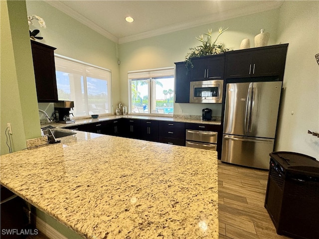 kitchen featuring light stone countertops, appliances with stainless steel finishes, light wood-type flooring, sink, and kitchen peninsula