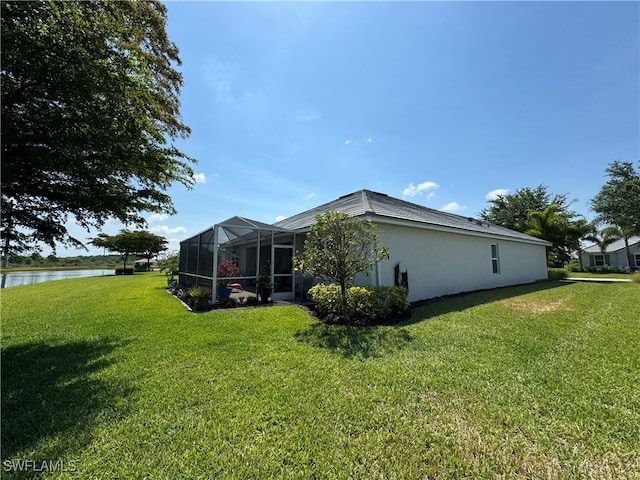 view of side of property featuring a water view, glass enclosure, and a yard