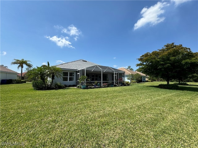 back of house with a lanai and a lawn