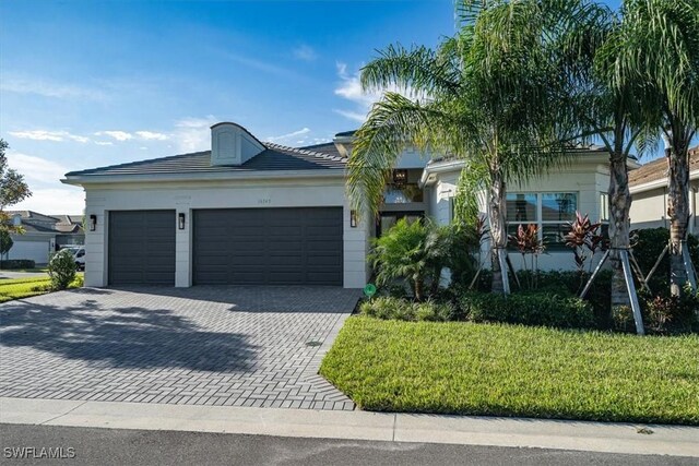 view of front of home featuring a garage, decorative driveway, and a front yard