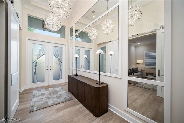 entryway featuring a notable chandelier, baseboards, a towering ceiling, french doors, and wood finished floors
