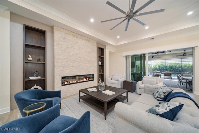 living room featuring a stone fireplace, built in features, light wood-type flooring, and ceiling fan