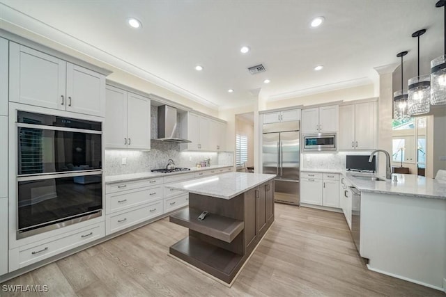 kitchen with built in appliances, visible vents, a wealth of natural light, and wall chimney exhaust hood