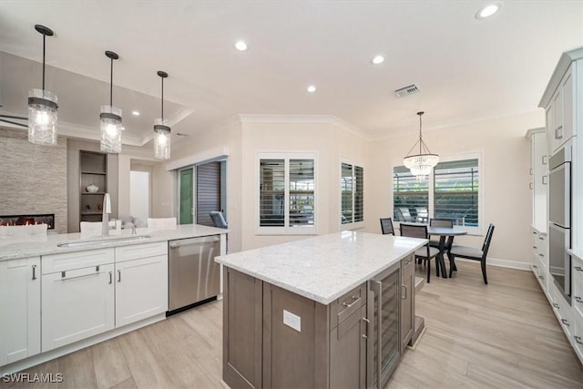 kitchen featuring a sink, visible vents, dishwasher, light wood finished floors, and ornamental molding