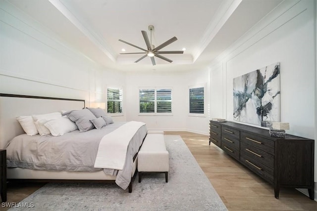 bedroom with crown molding, recessed lighting, a tray ceiling, and light wood-style floors