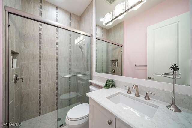 bathroom featuring a stall shower, toilet, and vanity