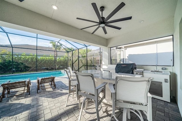 view of patio / terrace with exterior kitchen, grilling area, a ceiling fan, and an outdoor pool