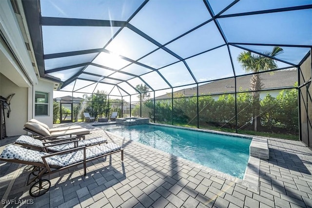 view of pool featuring glass enclosure, a pool with connected hot tub, and a patio area