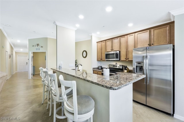 kitchen featuring a kitchen breakfast bar, ornamental molding, light stone counters, kitchen peninsula, and stainless steel appliances