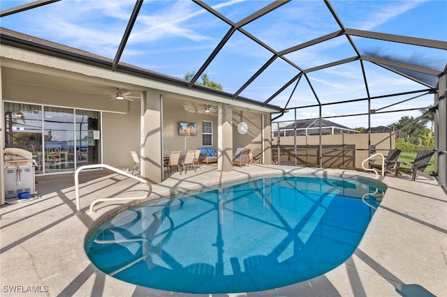 view of swimming pool featuring ceiling fan, a lanai, and a patio