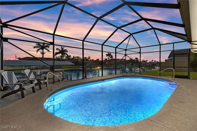 pool at dusk with a water view, a patio area, and a lanai