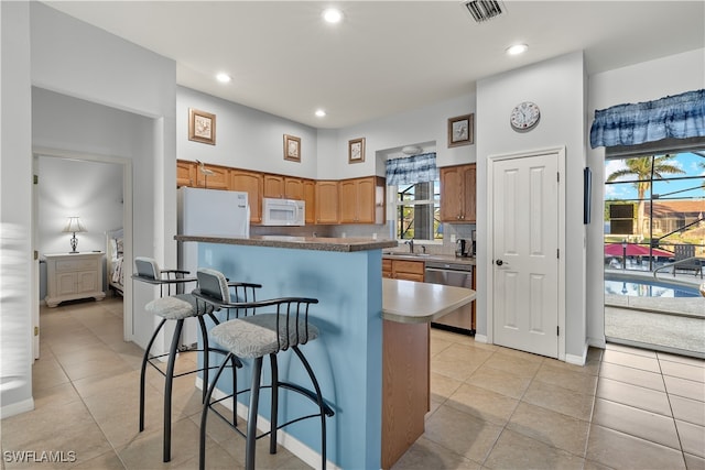 kitchen featuring plenty of natural light, a kitchen island, white appliances, and light tile patterned floors