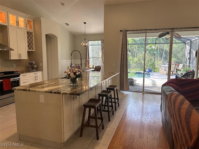 kitchen with white cabinetry, a large island with sink, electric range, and decorative light fixtures