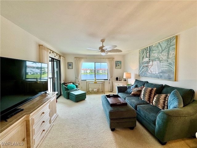 carpeted living room with a water view and ceiling fan