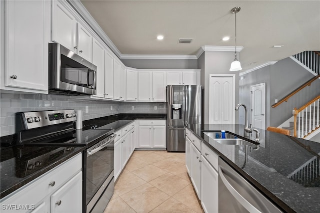 kitchen with white cabinets, appliances with stainless steel finishes, dark stone countertops, decorative light fixtures, and sink