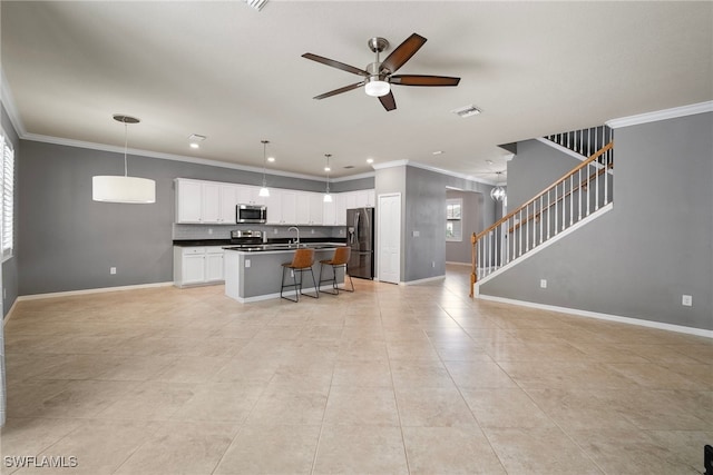 kitchen with ornamental molding, white cabinetry, stainless steel appliances, and an island with sink