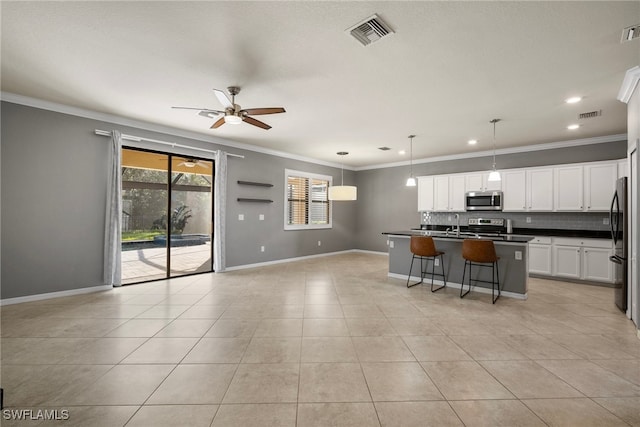 kitchen with hanging light fixtures, stainless steel appliances, backsplash, crown molding, and white cabinetry