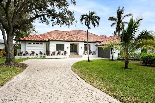 mediterranean / spanish-style home featuring a garage and a front yard