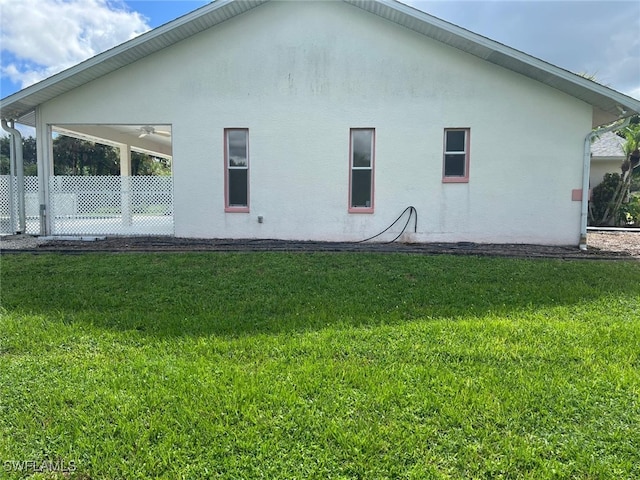 back of house featuring ceiling fan and a lawn