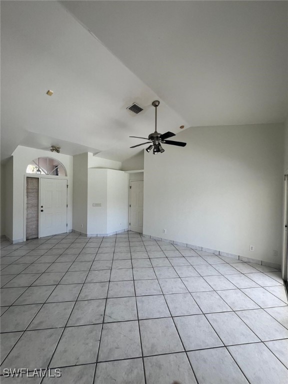 unfurnished living room with ceiling fan, light tile patterned floors, and vaulted ceiling