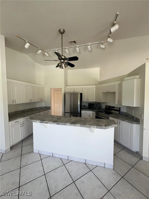 kitchen with light tile patterned flooring, ceiling fan, stainless steel appliances, vaulted ceiling, and white cabinets