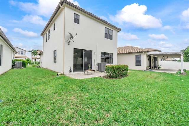 rear view of house with cooling unit, a patio area, and a lawn