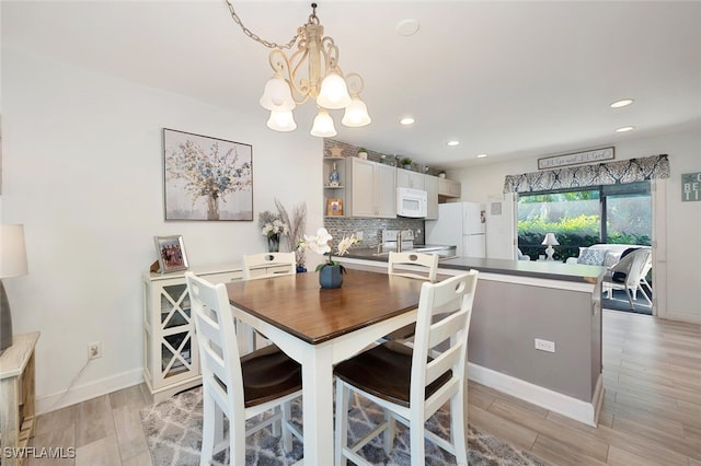 dining space with light wood-type flooring and a chandelier