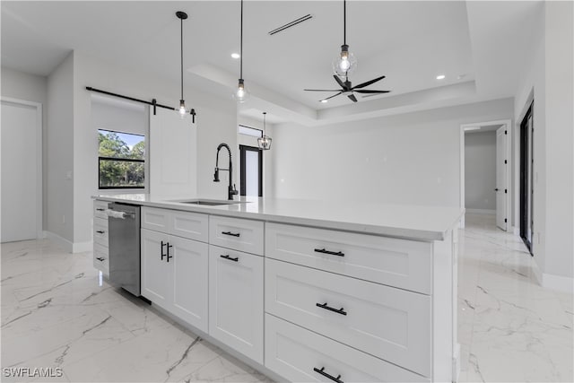 kitchen featuring a center island with sink, a barn door, white cabinets, and a raised ceiling