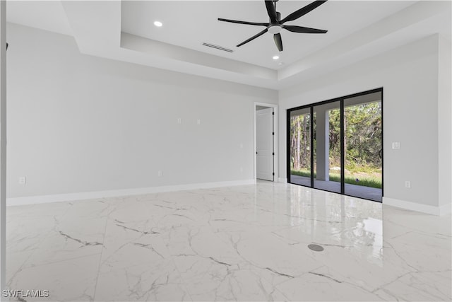 spare room with ceiling fan and a raised ceiling