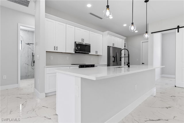 kitchen featuring white cabinetry, stainless steel appliances, an island with sink, and a barn door