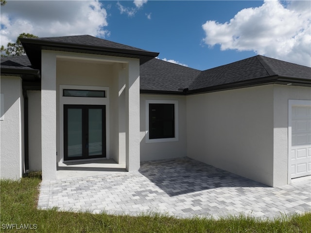 view of exterior entry featuring a garage and a patio