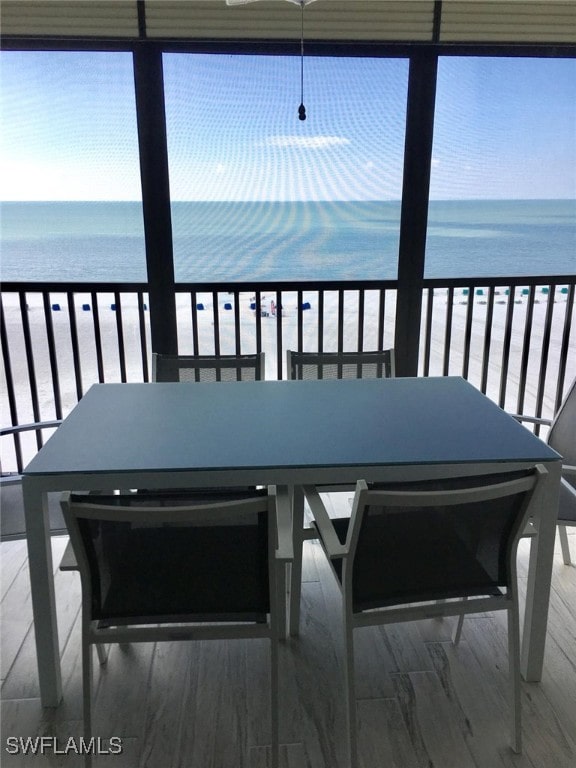 sunroom featuring a water view and a view of the beach