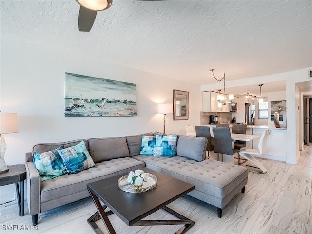 living room with a textured ceiling and ceiling fan with notable chandelier