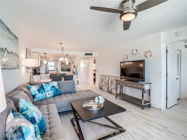 living room with a textured ceiling, light hardwood / wood-style flooring, and ceiling fan