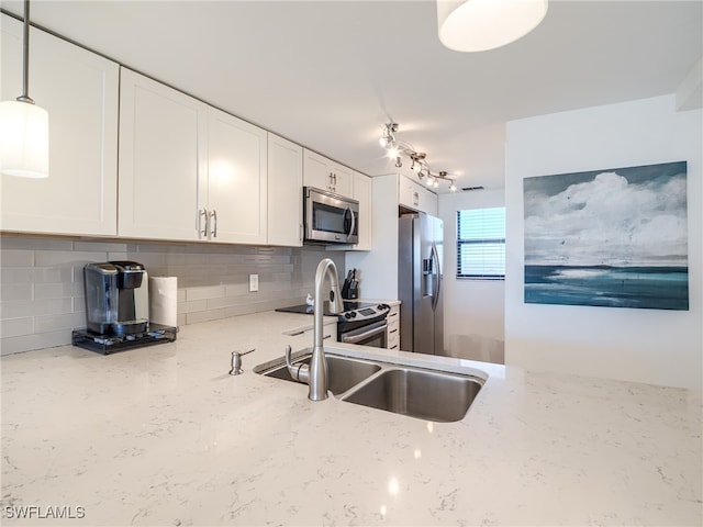 kitchen with appliances with stainless steel finishes, decorative light fixtures, light stone countertops, decorative backsplash, and white cabinets