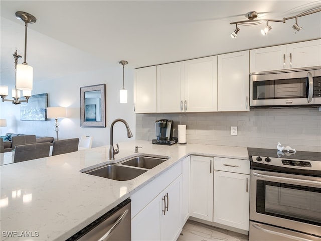 kitchen with sink, tasteful backsplash, pendant lighting, appliances with stainless steel finishes, and white cabinetry