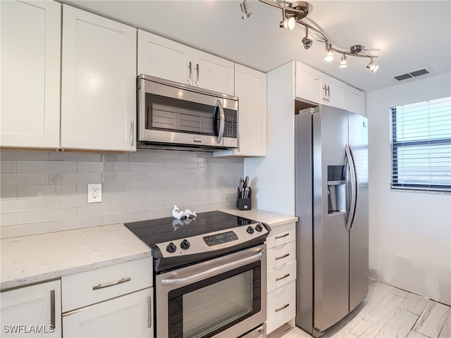 kitchen with white cabinetry, decorative backsplash, appliances with stainless steel finishes, and light stone counters