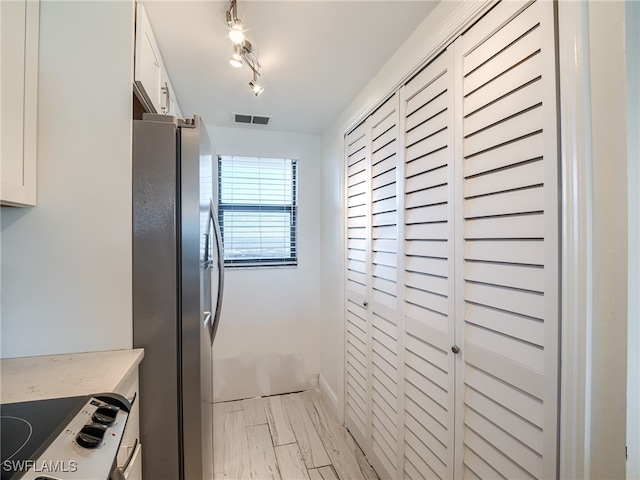 kitchen with white electric stove, white cabinetry, and stainless steel refrigerator