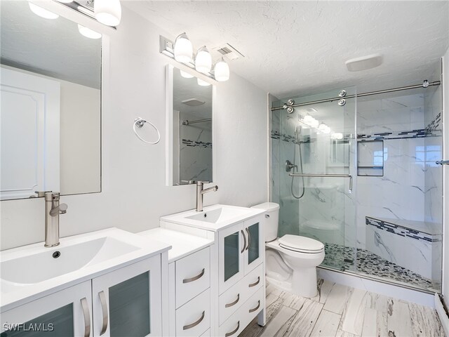 bathroom with toilet, vanity, an enclosed shower, and a textured ceiling