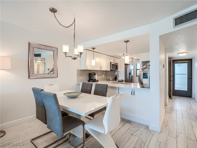 dining room featuring light hardwood / wood-style floors, sink, and an inviting chandelier