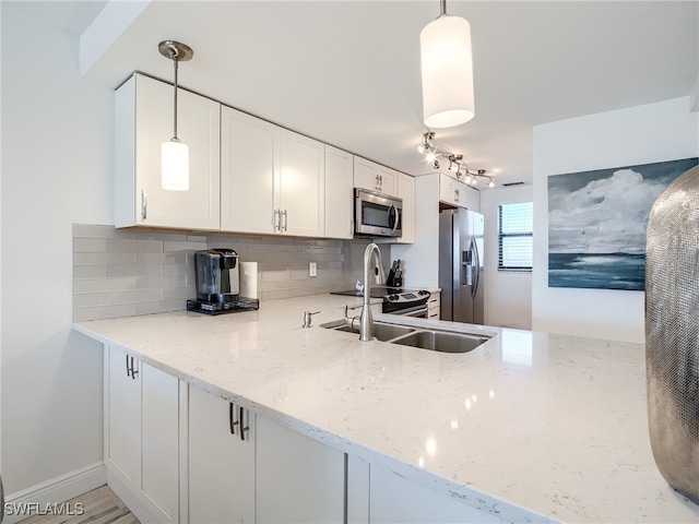 kitchen featuring tasteful backsplash, light stone counters, white cabinetry, appliances with stainless steel finishes, and pendant lighting