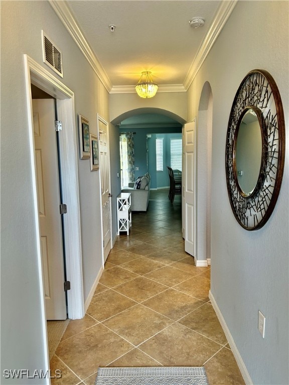 hall with crown molding, light tile patterned flooring, and an inviting chandelier