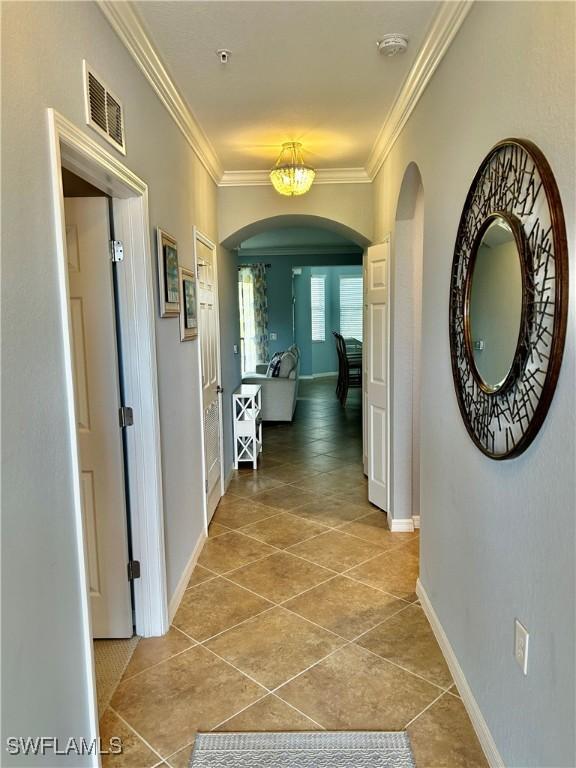 9834 Giaveno Cir Unit 1723, Naples, FL 34113 - hallway with visible vents, light tile patterned floors, arched walkways, crown molding, and baseboards