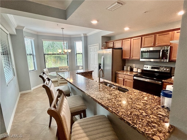 kitchen with sink, stainless steel appliances, dark stone counters, pendant lighting, and an inviting chandelier