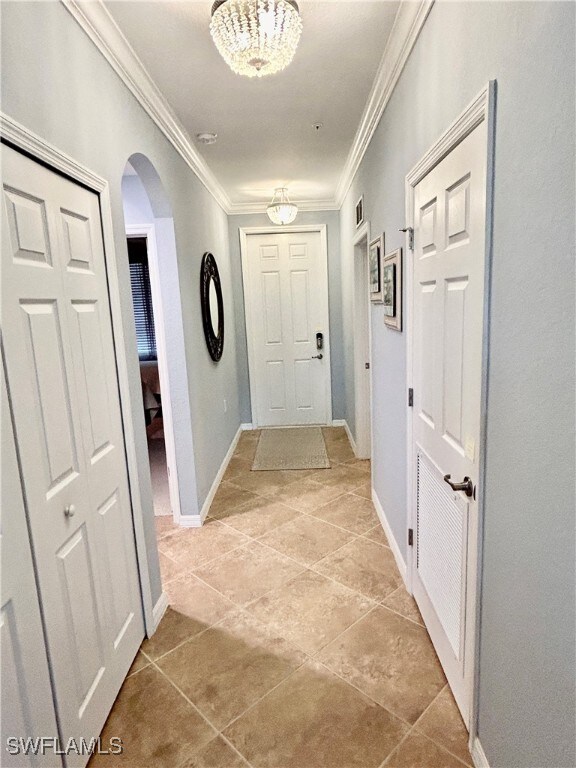 hallway featuring crown molding, light tile patterned flooring, and a chandelier