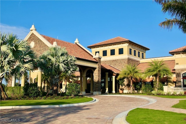 9834 Giaveno Cir Unit 1723, Naples, FL 34113 - mediterranean / spanish-style house featuring a tile roof, stone siding, stucco siding, and curved driveway