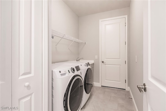 laundry room with light tile patterned floors and washer and clothes dryer